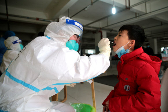 지난 4일 중국 산시성 시안에서 한 의사가 어린이에게 코로나19 검사를 하고 있다. 현재 시안은 감염병 차단을 위해 도시 전체가 2주 이상 봉쇄돼 있다. 시안 로이터 연합뉴스