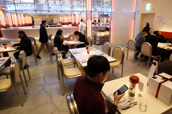 영국 출신의 스타 셰프 고든 램지의 버거 레스토랑인 ‘고든 램지 버거’가 정식 오픈한 7일 오전 서울 잠실 롯데월드몰의 매장에서 고객들이 식사를 기다리고 있다. 이번에 내는 매장은 전 세계 4호점이자 아시아 첫 매장이다. 2022.1.7  연합뉴스