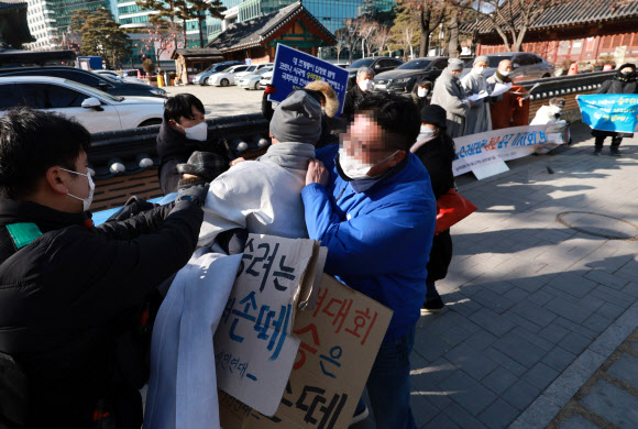 ‘승려대회 취소를 요구하는 불제자’라는 이름으로 모인 승려와 불교 신도들이 13일 오후 서울 종로구 견지동 조계사 앞에서 “코로나 시국에 국민을 불안하게 하는 승려대회를 취소하라”고 요구하며 기자회견을 하던 중 회견 내용에 반대하는 한 승려가 다가와 회견 참석자가 들고 있던 팻말을 뺏어 찢은 뒤 회견 중단을 요구하고 있다. 2022.1.13  연합뉴스