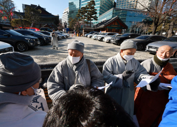 ‘승려대회 취소를 요구하는 불제자’라는 이름으로 모인 승려와 불교 신도들이 13일 오후 서울 종로구 견지동 조계사 앞에서 “코로나 시국에 국민을 불안하게 하는 승려대회를 취소하라”고 요구하며 기자회견을 하던 중 회견 내용에 반대하는 한 승려가 다가와 회견 참석자가 들고 있던 팻말을 뺏어 찢은 뒤 회견 중단을 요구하고 있다. 2022.1.13  연합뉴스