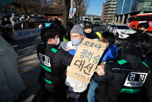 ‘승려대회 취소를 요구하는 불제자’라는 이름으로 모인 승려와 불교 신도들이 13일 오후 서울 종로구 견지동 조계사 앞에서 “코로나 시국에 국민을 불안하게 하는 승려대회를 취소하라”고 요구하며 기자회견을 하던 중 회견 내용에 반대하는 한 승려가 다가와 회견 참석자가 들고 있던 팻말을 뺏어 찢은 뒤 회견 중단을 요구하자 경찰이 이를 제지하고 있다. 2022.1.13  연합뉴스
