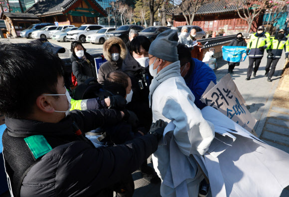 ‘승려대회 취소를 요구하는 불제자’라는 이름으로 모인 승려와 불교 신도들이 13일 오후 서울 종로구 견지동 조계사 앞에서 “코로나 시국에 국민을 불안하게 하는 승려대회를 취소하라”고 요구하며 기자회견을 하던 중 회견 내용에 반대하는 한 승려가 다가와 회견 참석자가 들고 있던 팻말을 뺏어 찢은 뒤 회견 중단을 요구하고 있다. 2022.1.13  연합뉴스