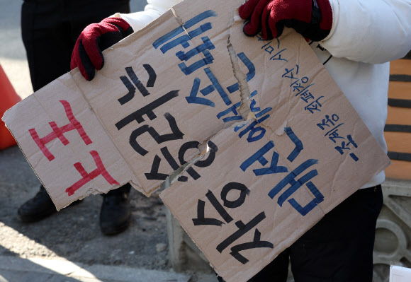 13일 오후 서울 종로구 견지동 조계사 앞에서 ‘승려대회 취소를 요구하는 불제자’라는 이름으로 모인 승려와 불교 신도들이 “코로나 시국에 국민을 불안하게 하는 승려대회를 취소하라”고 요구하며 기자회견을 하던 중 회견 내용에 반대하는 한 승려가 다가와 회견 참석자가 들고 있던 팻말을 뺏어 찢은 뒤 회견 중단을 요구했다.  한 회견 참가자가 승려와 실랑이 뒤 찢긴 팻말을 들고 있다. 2022.1.13  연합뉴스