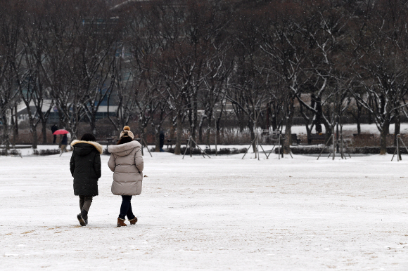 눈이 내리는 19일 서울 보라매공원에서 시민들이 눈을 밟으며 산책을 하고 있다. 2022.1.19 오장환 기자