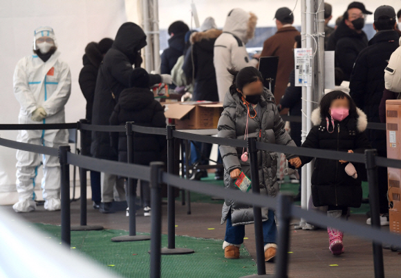 19일 서울 송파구청에 마련된 선별진료소에서 어린이들이 코로나19 검사를 받기 위해 줄을 서 있다. 의료진이 코로나 19 검사를 하고 있다. 2022.1.19 박지환기자