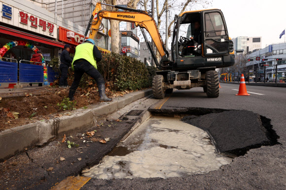 23일 싱크홀(지반 침하) 현상이 발생한 서울 종로구 종로5가역 인근 도로에서 관계자들이 복구작업을 하고 있다. 소방과 서울시 등 관계 당국에 따르면 이날 오후 12시 5분께 서울 종로5가역 인근 한 도로에서 가로 3m, 세로 2m, 깊이 1m의 싱크홀이 발생했다. 서울시는 상수도관 파열로 인한 지반 유실로 싱크홀이 발생한 것으로 보고 정확한 원인을 조사 중이다. 2022.1.23  연합뉴스