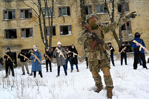 30일(현지시간) 우크라이나 수도 키예프에서 국토방위군의 한 교관이 칼라시니코프 소총의 나무 복제품을 든 민간인들을 가르치고 있다. 키예프 AFP 연합뉴스