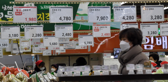 8일 서울의 한 대형마트를 찾은 고객 뒤로 무, 우엉, 연근 등 농산물들의 가격표가 걸려 있다. 소비자물가 상승률이 지난해 10월부터 지난달까지 넉 달 연속 3%대로 고공행진하는 가운데 서민들의 시름이 깊어지고 있다.  정연호 기자