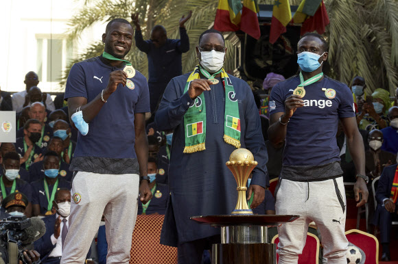 마키 살(가운데) 세네갈 대통령이 8일(현지시간) 세네갈 다카르 대통령궁에서 열린 축구대표팀 환영식에서 축구선수 칼리두 쿨리발리(왼쪽), 사디오 마네(오른쪽)와 함께 목에 건 아프리카 네이션스컵 우승 메달을 들어 보이고 있다. 다카르 AP 연합뉴스