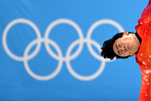 네이선 첸이 10일 베이징올림픽 피겨스케이팅 남자싱글 프리스케이팅에서 오륜마크를 배경으로 힘차게 스핀 연기를 펼치고 있다. [AFP 연합뉴스]