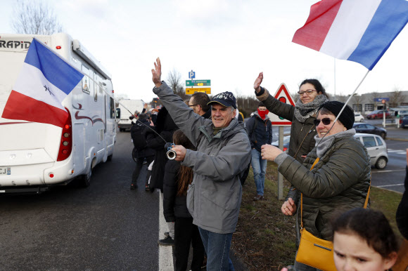 11일(현지시간) 프랑스 동부 스트라스부르에서 코로나19 백신 접종 의무화에 반대하는 시민들이 시위를 위해 파리로 향하는 차량들에 손을 흔들고 있다. 스트라스부르 AP 연합뉴스