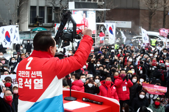윤석열 국민의힘 후보가 당의 색깔(빨간색)과 기호가 들어간 점퍼를 입고 선거운동을 하고 있는 모습.