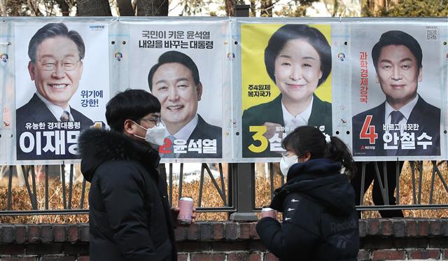 18일 서울 종로구 이화동 예술가의집 울타리 앞에서 시민들이 ‘제20대 대통령선거’에 출마하는 후보자들의 선거벽보를 살펴보고 있다. 2022.2.18 뉴스1