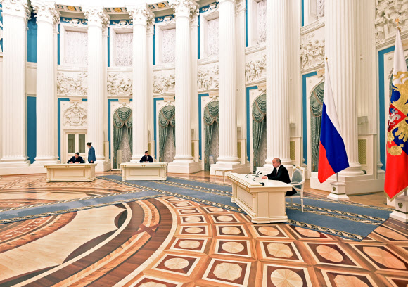 블라디미르 푸틴(오른쪽) 러시아 대통령이 21일(현지시간) 모스크바 크렘린궁에서 우크라이나 동부 돈바스 지역의 친러 분리주의 반군인 도네츠크인민공화국(DPR) 수장 데니스 푸슐린(가운데)과 루간스크인민공화국(LPR) 수장 레오니드 파세츠니크(왼쪽)와 함께 러시아가 DPR·LPR의 독립을 승인하는 문서에 서명하고 있다. 크렘린 제공 로이터 연합뉴스
