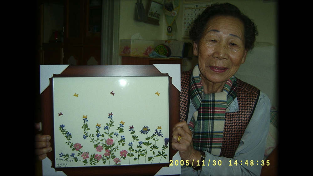 김순악 할머니가 생전 즐겨 작업하던 압화 작품을 들고 있는 모습. 인디플러그 제공