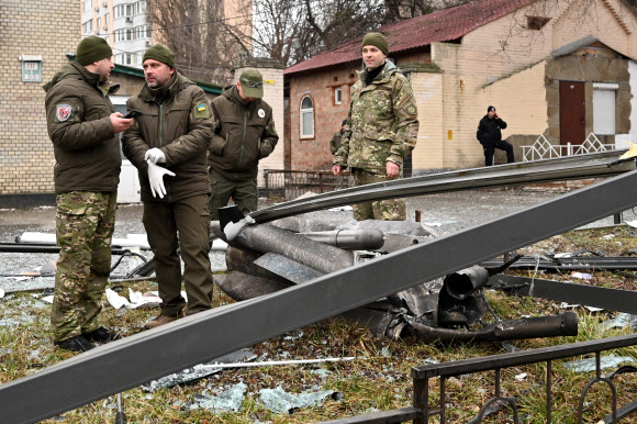 우크라이나 경찰이 24일(현지시간) 수도 키예프에 떨어진 미사일 잔해를 조사하고 있다. AFP 연합뉴스
