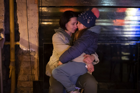 24일(현지시간) 우크라이나 키예프의 방공호로 쓰이는 한 건물 지하실에서 아이를 안고 있는 엄마. AP