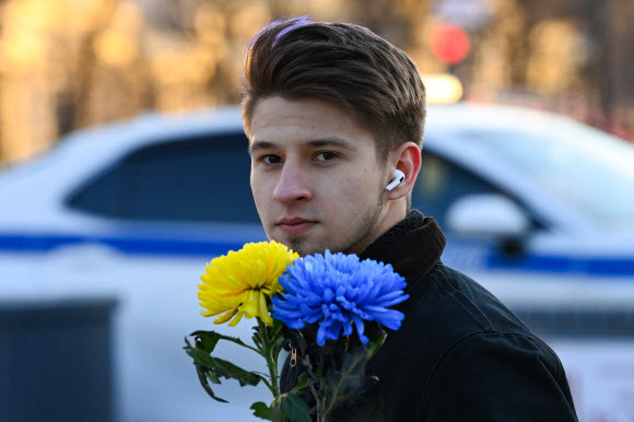 우크라이나 국기 색깔로 된 꽃을 든 남자가 24일(현지시간) 모스크바 중심부에서 열린 우크라이나 침공 반대 시위에 참가하고 있다. 모스크바 AFP 연합뉴스