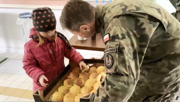 러시아가 우크라이나를 침범한 지 이틀째인 25일(현지시간) 한 우크라이나 소녀가 폴란드 프셰미실 역에 마련된 임시 난민수용소에서 간식으로 먹을 도넛을 고르고 있다. 2022.02.26 AP 연합뉴스