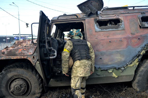러시아의 우크라이나 침공 나흘째인 27일(현지시간) 우크라이나 국토방위군(TDF) 대원이 하르키우 전투에서 파괴된 러시아군 전술차량 GAZ 티그르를 살펴보고 있다. 하르키우 AFP 연합뉴스