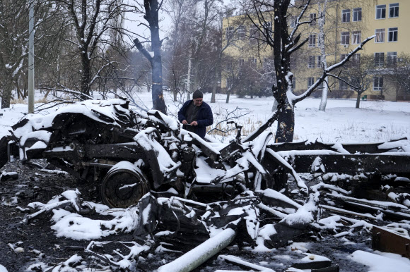 지난 25일(현지시간) 우크라이나 북동부 하리키우 외곽에서 한 우크라이나 남성이 파괴된 러시아 군용차량 옆에서 사진을 찍고 있다. 하르키우 AP 연합뉴스