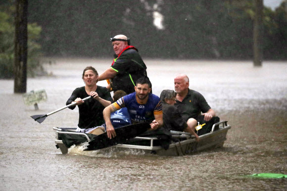 28일(현지시간) 호주 뉴사우스웨일스주 리스모어에 홍수가 발생하자 주민들이 소형 보트를 타고 침수 지역을 벗어나고 있다. AP 연합뉴스