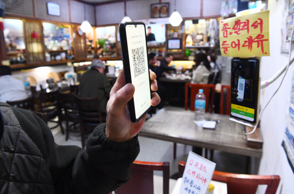 지난 달 28일 점심시간 서울 종로의 한 음식점에서 손님이 방역패스를 등록 하고 있다. 오늘부터 방역패스가 일시 중단된다. 안주영 전문기자