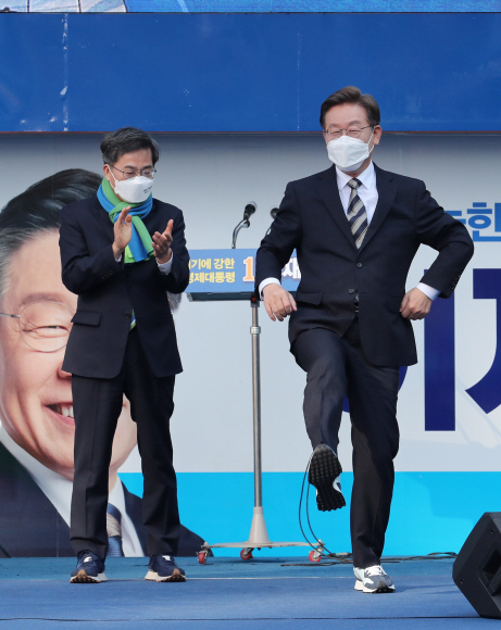 이재명 더불어민주당 대선 후보가 3일 서울 영등포구 타임스퀘어 앞 광장에서 열린 ‘영등포를 일등포로, 이재명은 합니다!’ 영등포 집중 유세에서 김동연 전 새로운물결 대선후보로부터 선물받은 운동화를 신어보고 있다.2022. 3. 3  김명국 선임기자