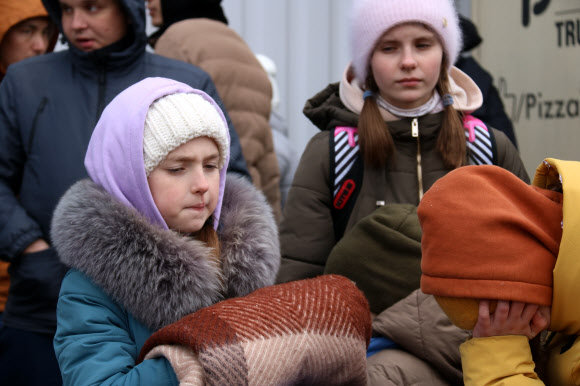 5일(현지시간) 폴란드 코르쵸바 국경검문소 인근 임시 난민수용시설 앞에 우크라이나 어린이들이 지친 표정으로 서 있다. 2022.3.6 연합뉴스