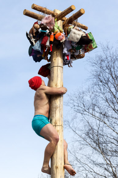 MOSCOW REGION, RUSSIA - MARCH 6, 2022: A man climbs a pole during Bakshevskaya Maslenitsa festival in the Pushkino District of the Moscow Region. Maslenitsa is a traditional Russian folk holiday celebrated during the week preceding the Lent. TASS 연합뉴스