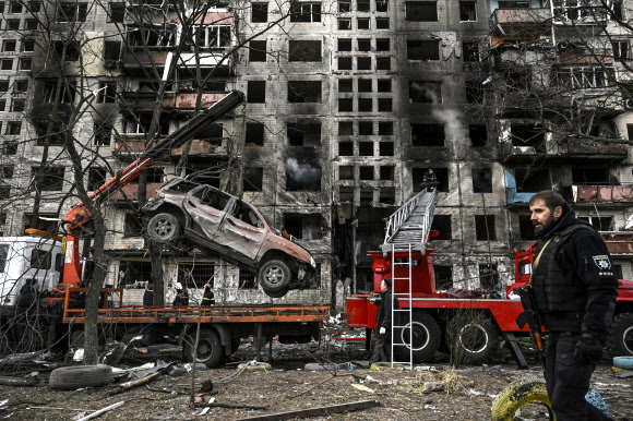 14일(현지시간) 우크라이나 키이우의 포격으로 파괴된 한 아파트에서 견인 트럭이 폐승용차 한 대를 옮기고 있다. 키이우 AFP 연합뉴스