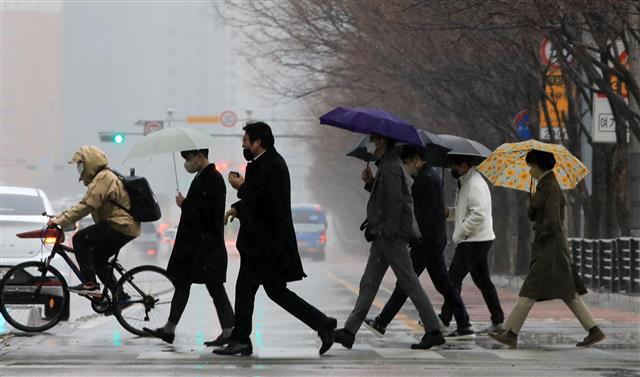 봄비가 쏟아지는 가운데 시민들이 14일 우산을 쓰고 서울 영등포구 여의도의 한 도로를 건너고 있다. 기상청은 이날 비가 내린 뒤부터 낮 최고기온이 10도를 웃도는 봄 날씨가 이어질 것이라고 전망했다. 뉴스1