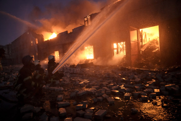 17일(현지시간) 우크라이나 수도 키이우 외곽에서 소방관들이 러시아군의 폭격을 받은 창고 건물의 불을 끄고 있다. AP 연합뉴스