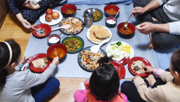 지난 13일 타예브씨 가족이 점심을 먹기 위해 아프가니스탄 음식을 차려놓고 빙 둘러앉아 있다. 안주영 전문기자