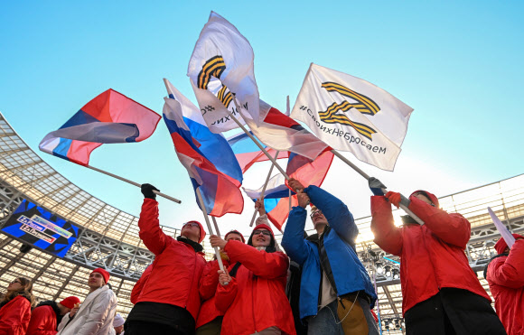 지난 18일 러시아 모스크바에서 열린 크름반도 합병 8주년 행사에서 푸틴을 지지하는 이들이 러시아 국기를 흔들며 환호하고 있다. 2022.03.21 AP 연합뉴스