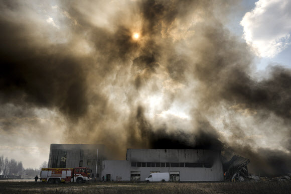 24일(현지시간) 우크라이나 키이우 외곽을 겨냥한 러시아군의 포격으로 부서진 창고 건물에서 검은 연기가 치솟고 있다. 2022.3.25 키이우 AP 연합뉴스
