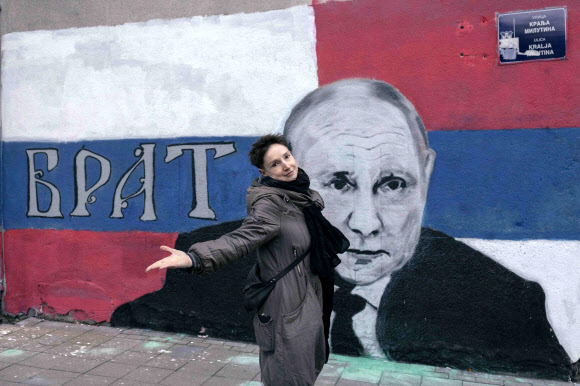 최근 러시아를 탈출해 세르비아 수도 베오그라드에 온 마리나(41)가 지난 17일(현지시간) 블라디미르 푸틴 대통령 벽화 앞에서 포즈를 취하고 있다. 베오그라드 AFP 연합뉴스
