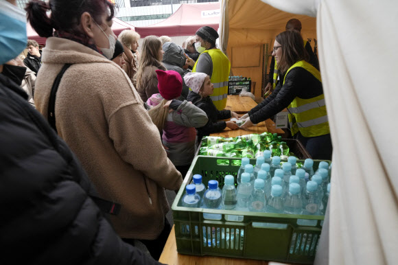 27일(현지시간) 우크라이나 난민들이 폴란드 바르샤바의 기차역에서 물과 음식을 받고 있다. AP