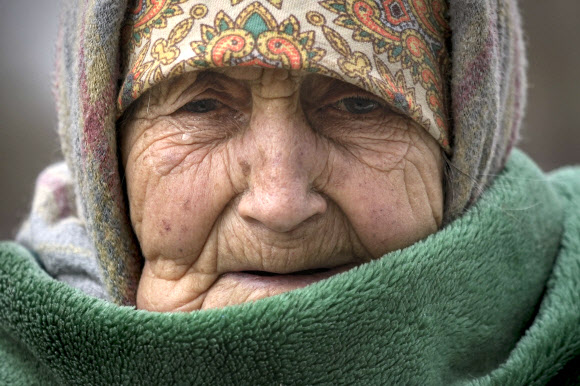 26일(현지시간) 우크라이나 키이우 인근에서 94세 할머니가 담요를 뒤집어 쓴 채 눈물을 흘리고 있다. AP