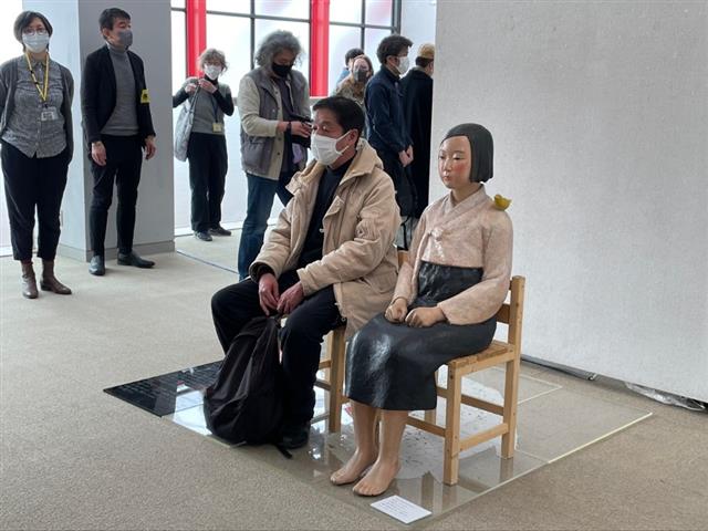 지난 2일 일본 도쿄도 구니타치시 구니타치시민예술홀 갤러리에서 열린 ‘표현의 부자유(不自由)전 도쿄 2022’에서 한 관람객이 ‘평화의 소녀상’ 옆에 앉아 작품을 감상하고 있다.