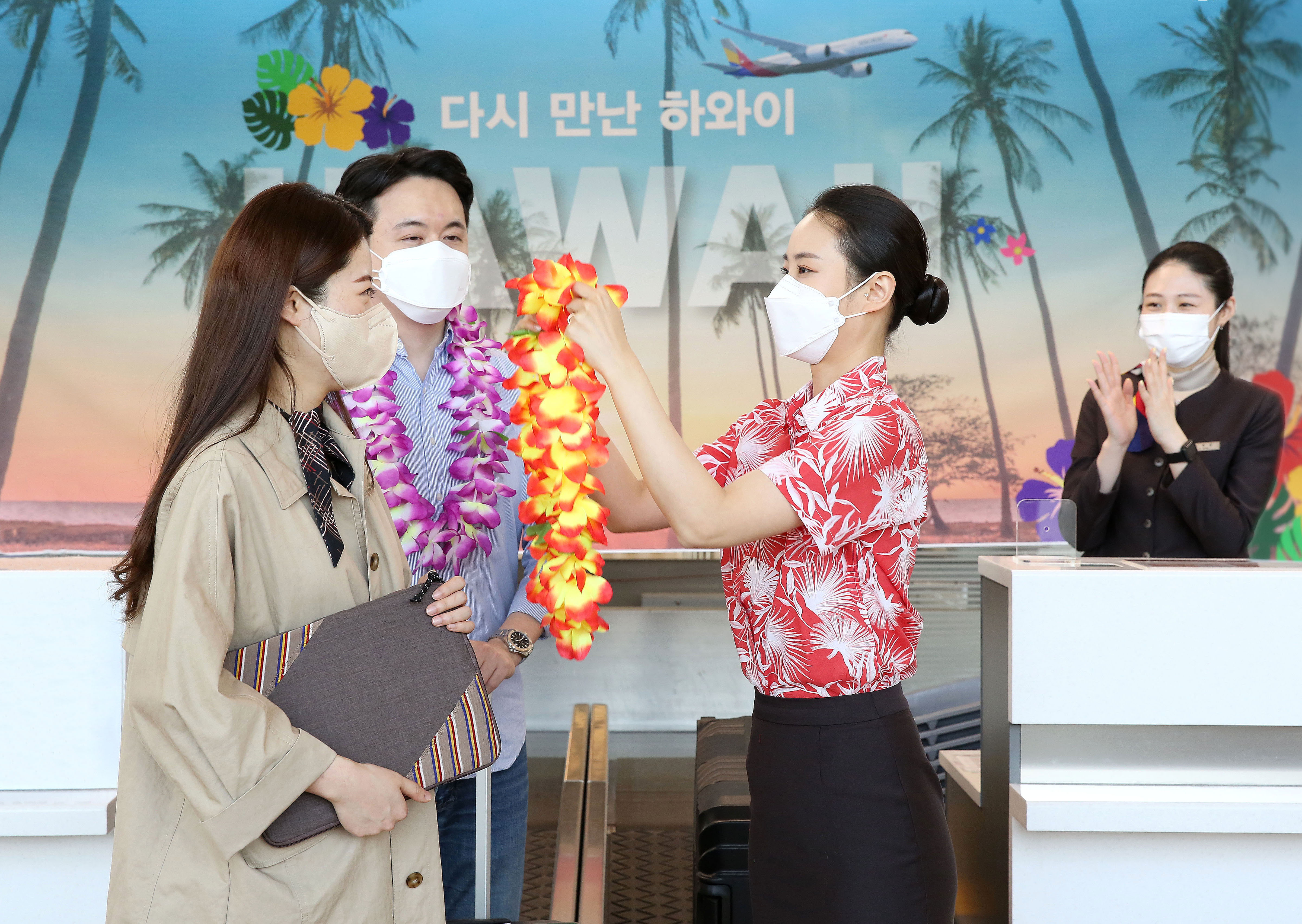 아시아나항공이 인천~하와이 노선 운행을 재개한 3일 인천국제공항 아시아나항공 카운터에서 한 직원이 탑승수속을 밟은 신혼 부부 승객에게 꽃다발을 걸어주고 있다. 아시아나항공 제공