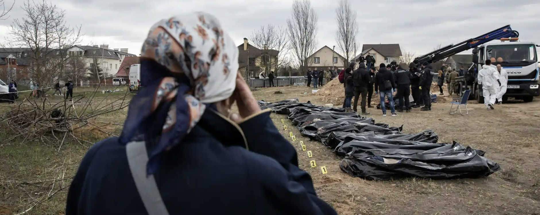 우크라이나 시민이 법의학팀이 부차에 있는 교회 부지에서 대규모 민간인 무덤을 발굴하는 것을 지켜보고 있다. 가디언 캡처  