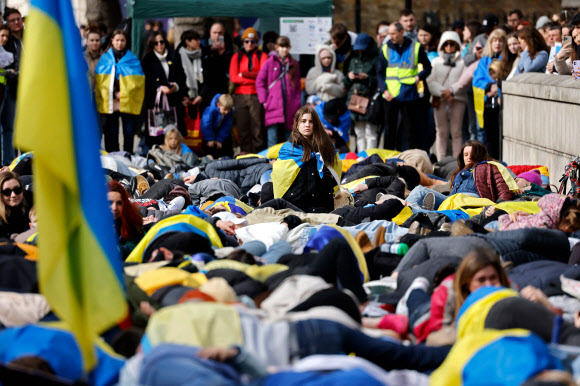 우크라이나 부차에서 러시아군이 저지른 민간인 학살을 규탄하는 사람들이 영국 총리 관저가 있는 런던 다우닝가 인근에서 학살로 죽어서 쓰러진 것 같은 모습으로 퍼포먼스를 펼치고 있다. 2022.4.9 AFP 연합뉴스