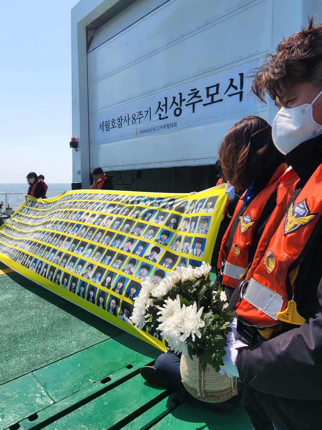 세월호 8주기였던 16일 진도군 조도면에서 열린 선상 추모식에 4.16재단 관계자들이 단원고 희생자들의 사진이 인쇄된 현수막을 들고 서있다.<br>곽소영 기자