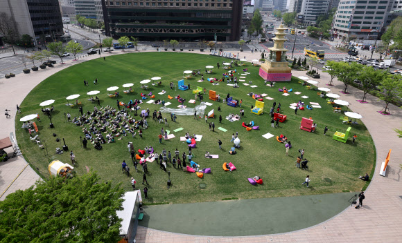 23일 서울광장에 설치된 야외도서관 ‘책 읽는 서울광장’에서 시민들이 잔디에 앉아 책을 읽으며 주말을 보내고 있다. 책 읽는 서울광장은 이날부터 오는 10월까지 매주 금요일과 토요일 운영된다. 2022.4.23  연합뉴스