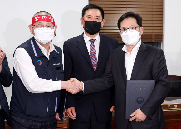 서울 시내버스 노사가 임금협상 1차 사후조정에서 협상을 타결한 26일 새벽 서울 영등포구 서울지방노동위원회에서 박점곤 서울시버스노동조합 위원장(왼쪽)과 조장우 서울시버스운송사업조합 이사장이 악수를 하고 있다. 2022.4.26  연합뉴스