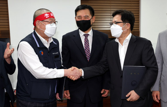 서울 시내버스 노사가 임금협상 1차 사후조정에서 협상을 타결한 26일 새벽 서울 영등포구 서울지방노동위원회에서 박점곤 서울시버스노동조합 위원장(왼쪽)과 조장우 서울시버스운송사업조합 이사장이 악수를 하고 있다. 2022.4.26  연합뉴스