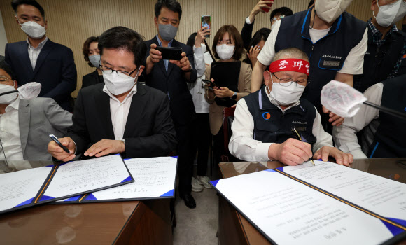 서울 시내버스 노사가 임금협상 1차 사후조정에서 협상을 타결한 26일 새벽 서울 영등포구 서울지방노동위원회에서 박점곤 서울시버스노동조합 위원장(오른쪽)과 조장우 서울시버스운송사업조합 이사장이 조정안에 사인을 하고 있다. 2022.4.26  연합뉴스