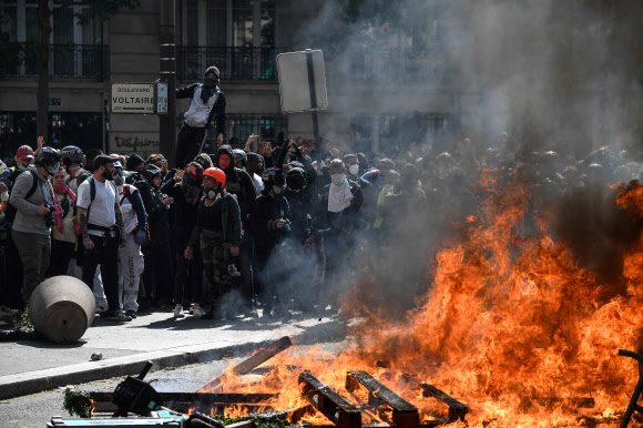 노동절인 1일(현지시간) 프랑스 파리에서 열린 집회에 참석한 복면 차림의 시위대가 시내 한복판의 불타는 시설물을 바라보고 있다. 이날 프랑스 전역에서 11만 6500여명이 반정부 시위에 참여했고 방화, 약탈 등 불법행위를 저지른 50여명이 경찰에 체포됐다. 파리 AFP 연합뉴스