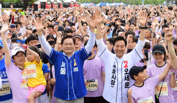 21일 서울 상암동 월드컵공원 일대에서 열린 2022 서울신문 마라톤대회에서 더불어민주당 송영길 서울시장 후보와 국민의힘 오세훈 서울시장 후보가 참가자들과 기념촬영을 하고 있다. 2022.5.21 정연호 기자